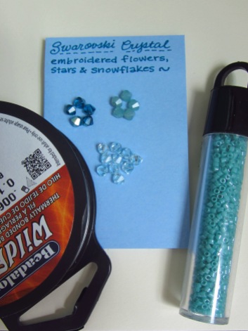 Materials: (1) Wildfire beading string (about 8"), (2) 4 mm bicone Swarovski crystal beads in different colors (as pictured, 5 pacific opal, 5 aquamarine satin, and 10 light azore) x 20 total beads, (3) seed beads (Pictured here, Delica brand aquamarine glass seed beads).